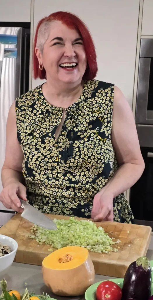 Anne in kitchen chopping veg and laughing