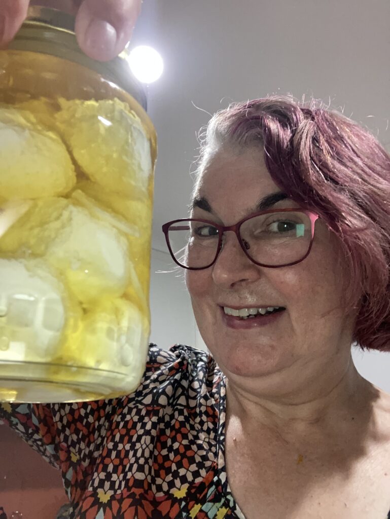 Anne holds jar of labne in olive oil aloft